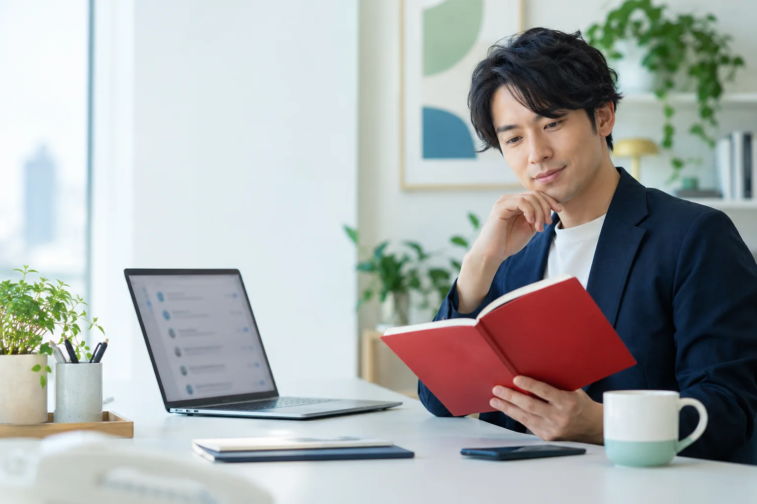 赤いノートを手に、PCで文章の条件を見直す架空の担当者